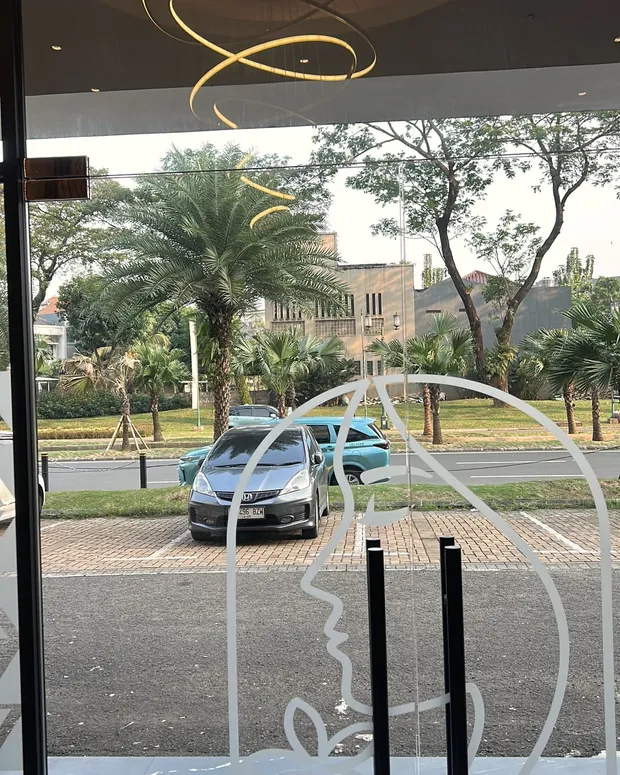 Pintu kaca depan Divine dengan siluet logo wanita dalam lengkung, menghadap Boulevard Gading Serpong