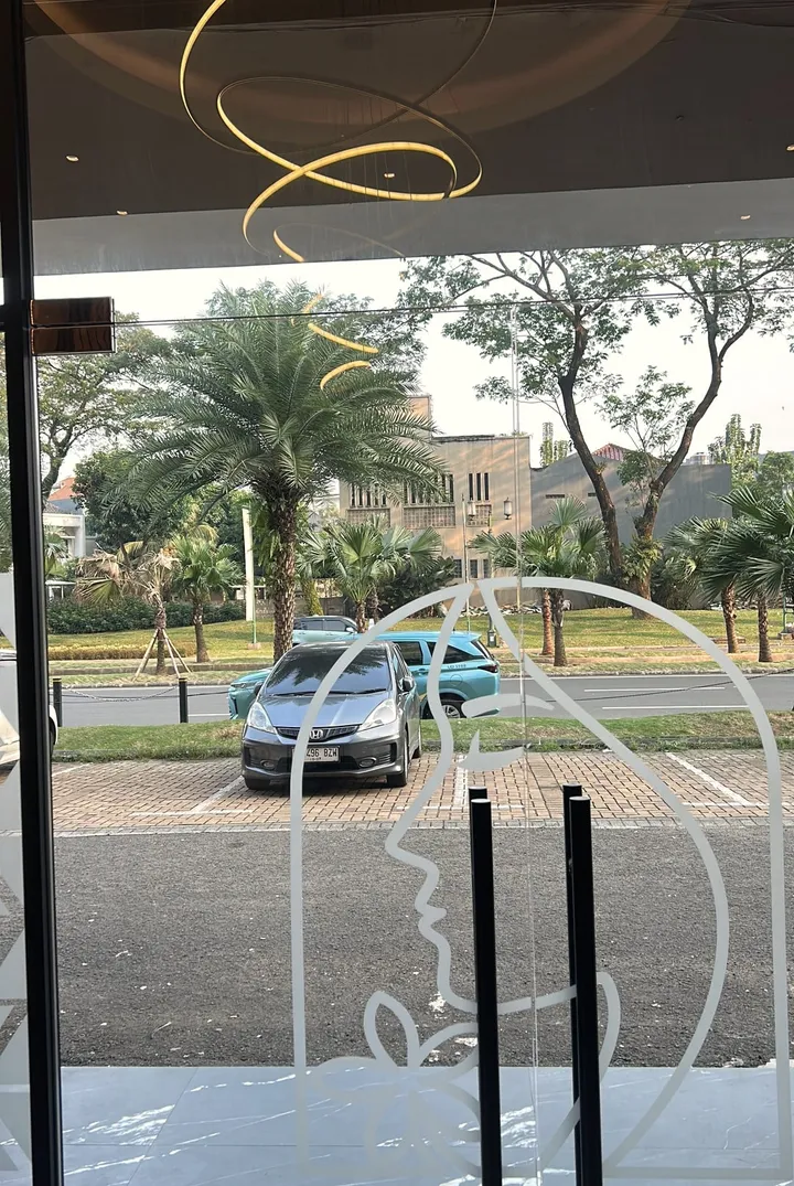Pintu kaca depan Divine dengan siluet logo wanita dalam lengkung, menghadap Boulevard Gading Serpong