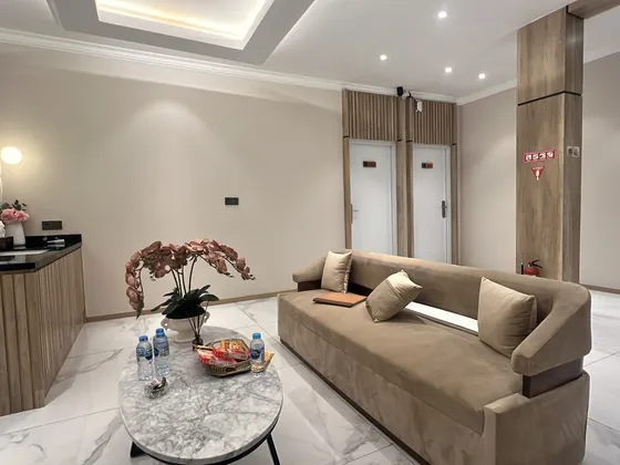 Ruang tunggu dengan sofa beludru krem dan meja marmer bundar