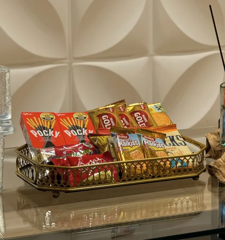 Nampan emas berisi aneka snack gratis di meja kaca lounge