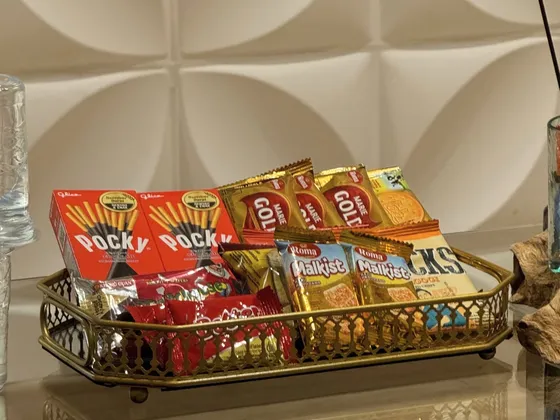 Nampan emas berisi aneka snack gratis di meja kaca lounge